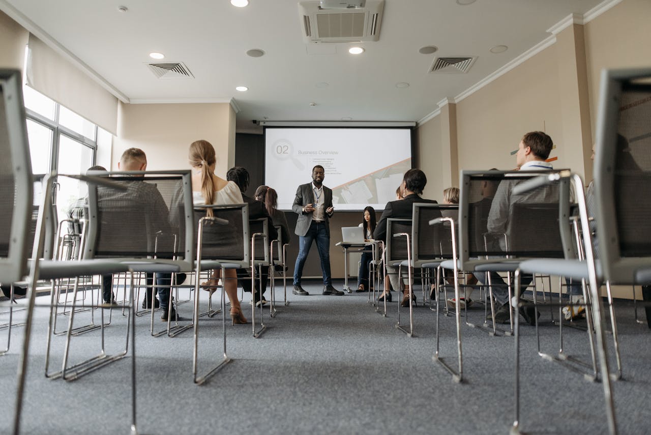 Business seminar with a diverse group, featuring a speaker in a modern conference room.