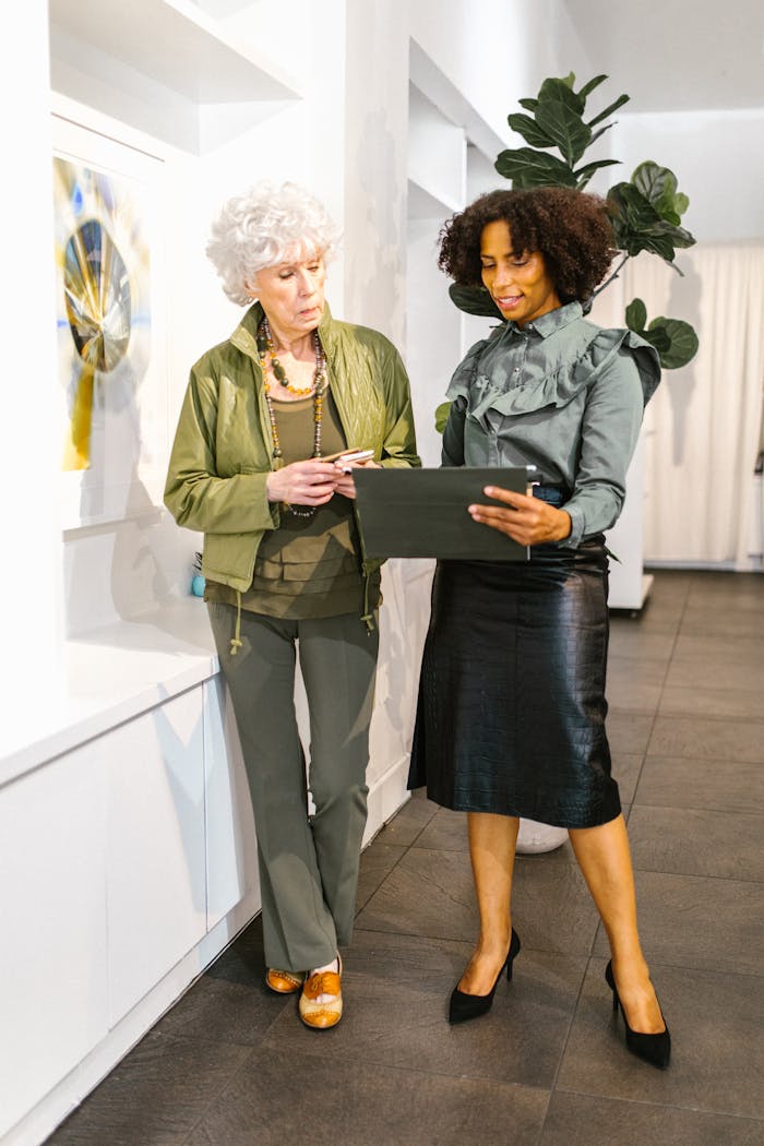 Home Elegant businesswomen in discussion, reviewing documents in modern office.